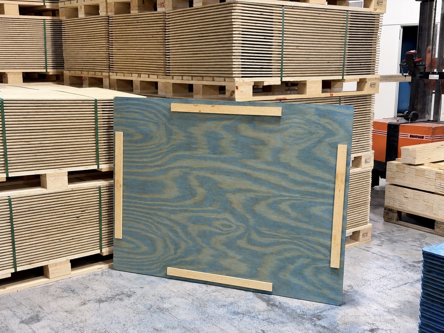 Plywood lid with four wooden battens in front of stacks of plywood lids